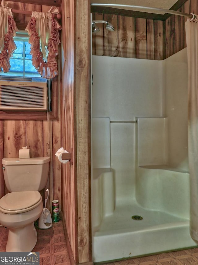 bathroom featuring walk in shower, cooling unit, wooden walls, and toilet