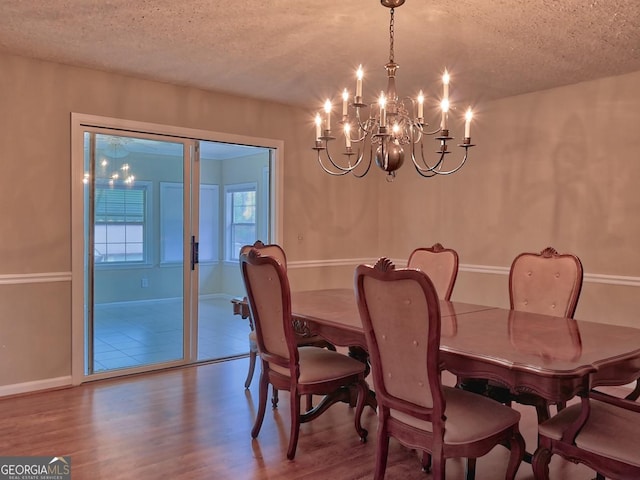 dining space with a textured ceiling, a notable chandelier, and hardwood / wood-style floors