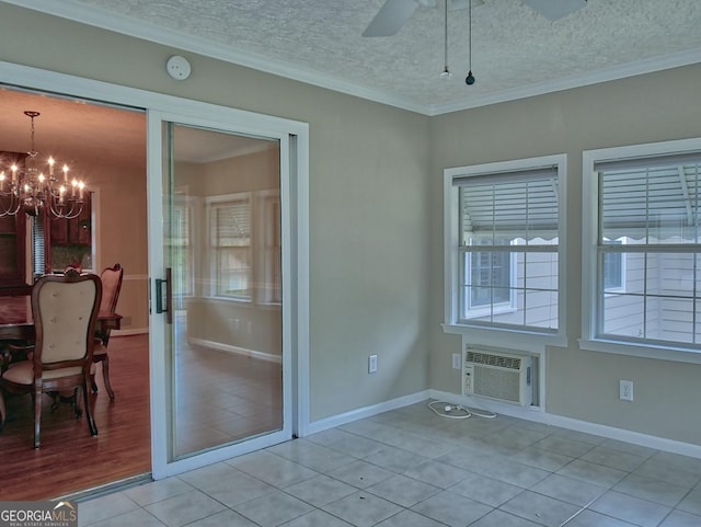 interior space with a textured ceiling, light tile patterned flooring, ornamental molding, ceiling fan with notable chandelier, and a wall unit AC