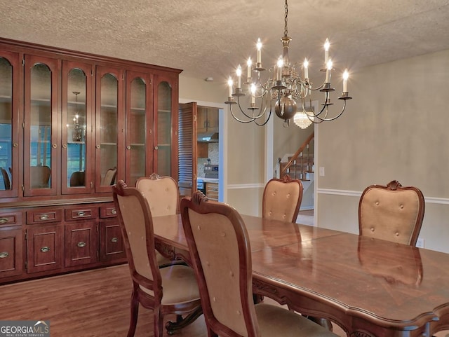 dining area with hardwood / wood-style floors, an inviting chandelier, and a textured ceiling