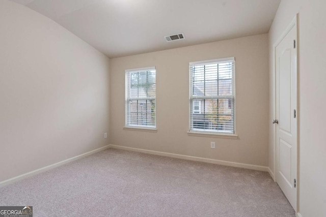 empty room with lofted ceiling and light colored carpet