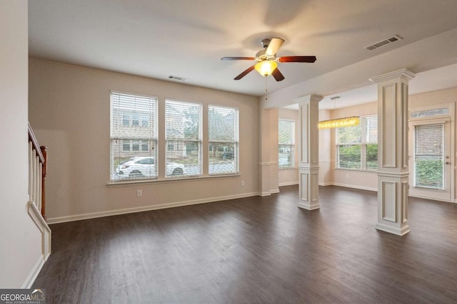 unfurnished living room with decorative columns, dark wood-type flooring, ceiling fan, and a wealth of natural light