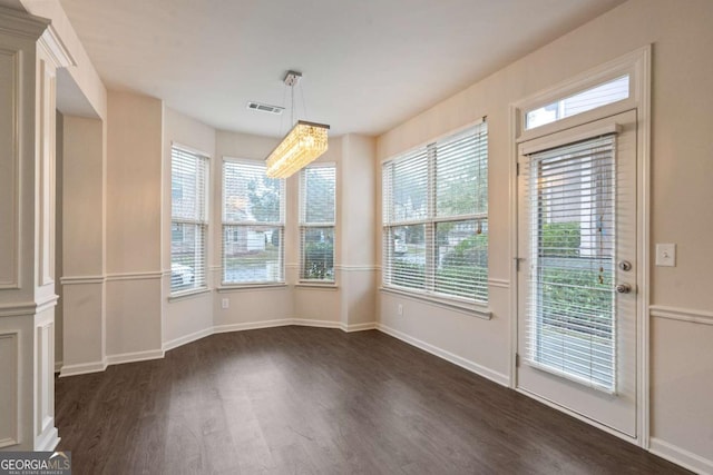 unfurnished dining area featuring a notable chandelier and dark hardwood / wood-style floors