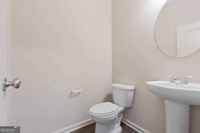 bathroom featuring toilet, wood-type flooring, and sink