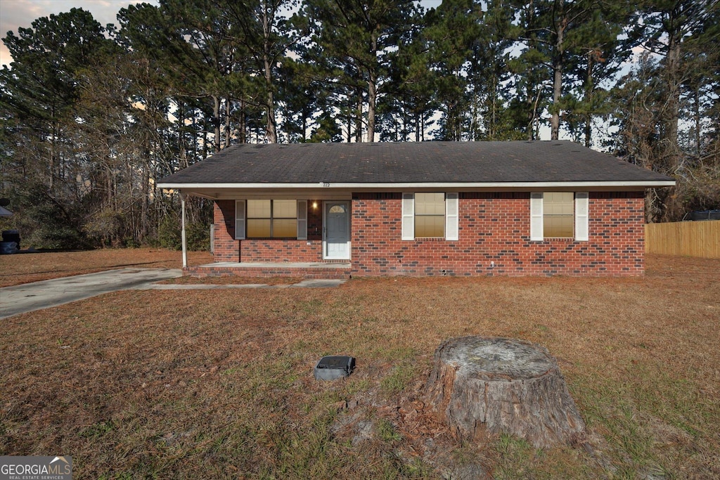 ranch-style home with covered porch and a yard