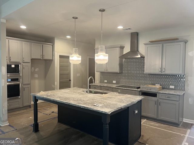 kitchen featuring gray cabinets, stainless steel appliances, an island with sink, wall chimney exhaust hood, and sink