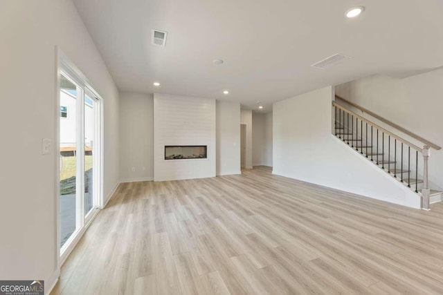 unfurnished living room with a large fireplace and light hardwood / wood-style flooring