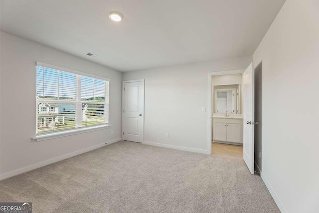 unfurnished bedroom with light colored carpet, a closet, and connected bathroom