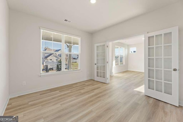 empty room with light hardwood / wood-style flooring and french doors