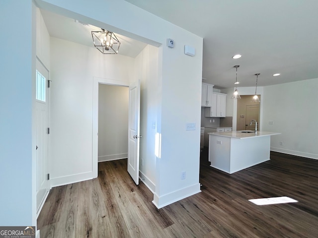 kitchen with decorative light fixtures, an inviting chandelier, a kitchen island with sink, white cabinets, and sink