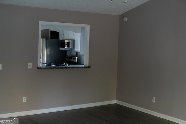 spare room with a textured ceiling and dark hardwood / wood-style floors