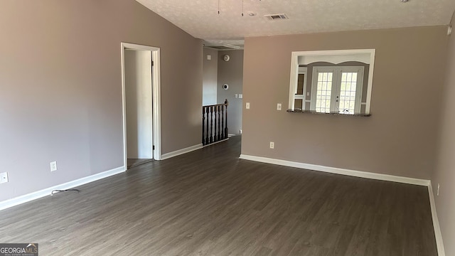 empty room featuring a textured ceiling, french doors, and dark hardwood / wood-style flooring