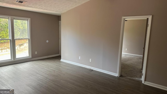 empty room featuring a textured ceiling and dark hardwood / wood-style flooring