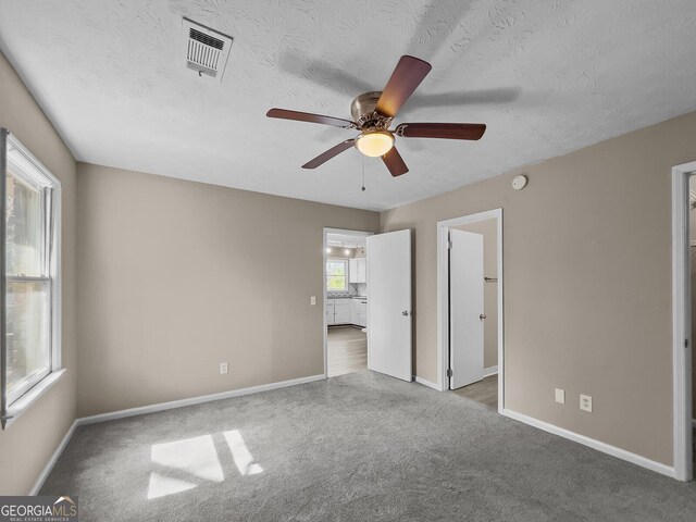 carpeted empty room featuring a textured ceiling and ceiling fan