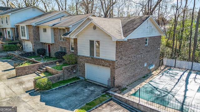 view of front of home with aphalt driveway, an attached garage, brick siding, and fence