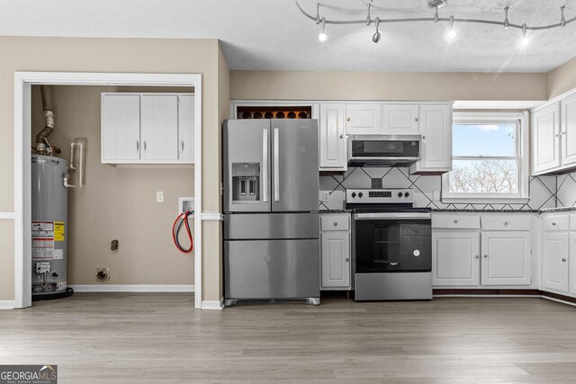 kitchen with a textured ceiling, rail lighting, white cabinetry, appliances with stainless steel finishes, and sink