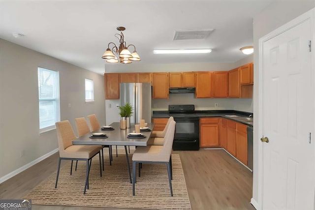 kitchen featuring black electric range, decorative light fixtures, stainless steel refrigerator, a chandelier, and light hardwood / wood-style flooring