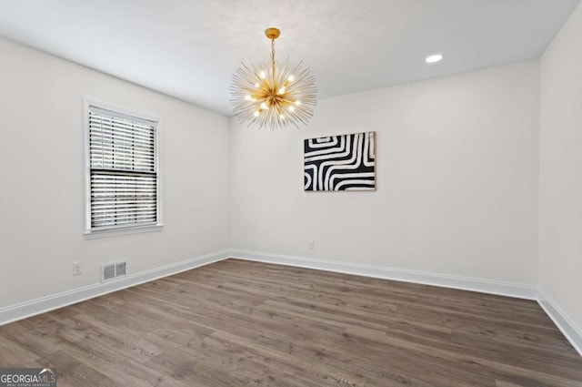 empty room featuring dark hardwood / wood-style floors and a chandelier