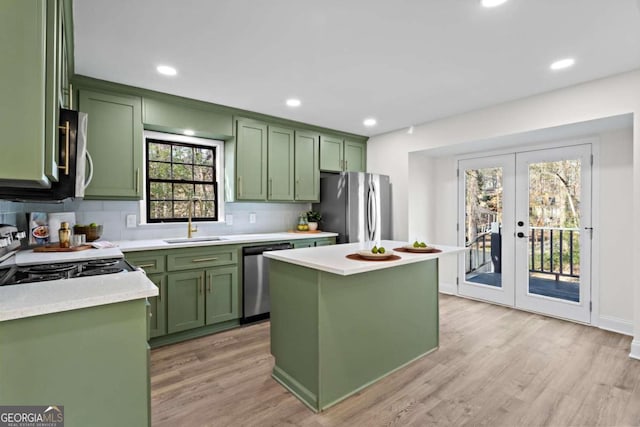 kitchen featuring stainless steel appliances, french doors, tasteful backsplash, a kitchen island, and sink