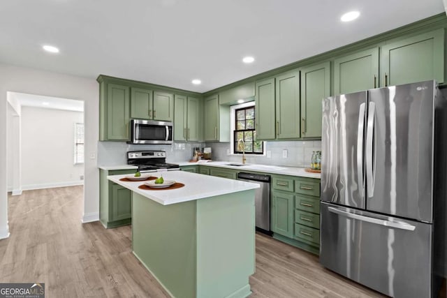 kitchen with stainless steel appliances, a kitchen island, light wood-type flooring, and green cabinetry