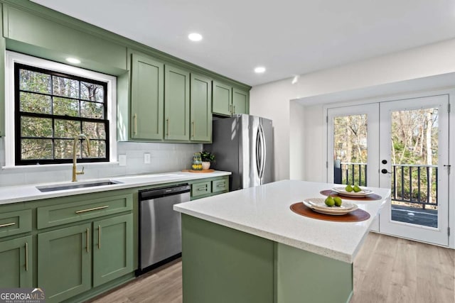 kitchen with stainless steel appliances, green cabinetry, tasteful backsplash, a kitchen island, and sink