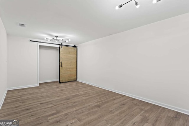 unfurnished room with hardwood / wood-style floors and a barn door