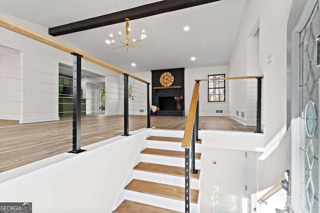 stairway with lofted ceiling with beams, a fireplace, and a chandelier