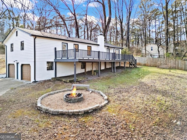 exterior space with an outdoor fire pit, a garage, and a wooden deck