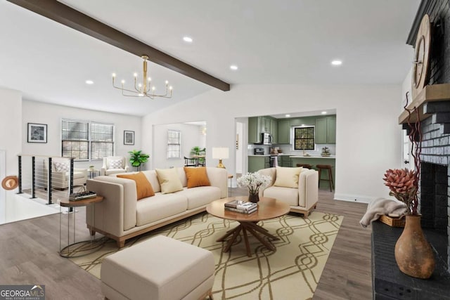 living room with hardwood / wood-style floors, an inviting chandelier, lofted ceiling with beams, and a fireplace