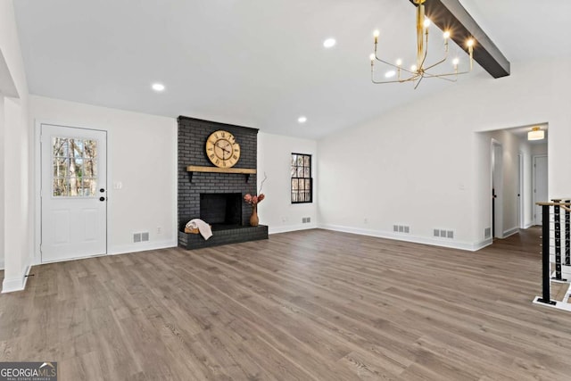 unfurnished living room with a brick fireplace, an inviting chandelier, hardwood / wood-style floors, and beamed ceiling