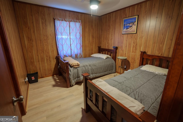 bedroom with light wood-type flooring, ceiling fan, and wooden walls