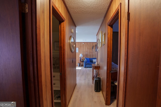 hall featuring ornamental molding, a textured ceiling, and wooden walls