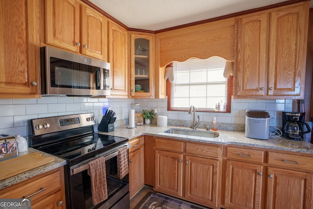 kitchen with sink, stainless steel appliances, backsplash, and light stone counters