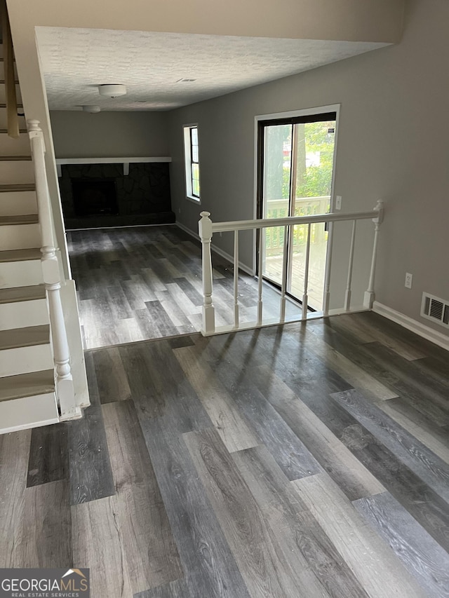 unfurnished room with a fireplace, a textured ceiling, and dark hardwood / wood-style floors