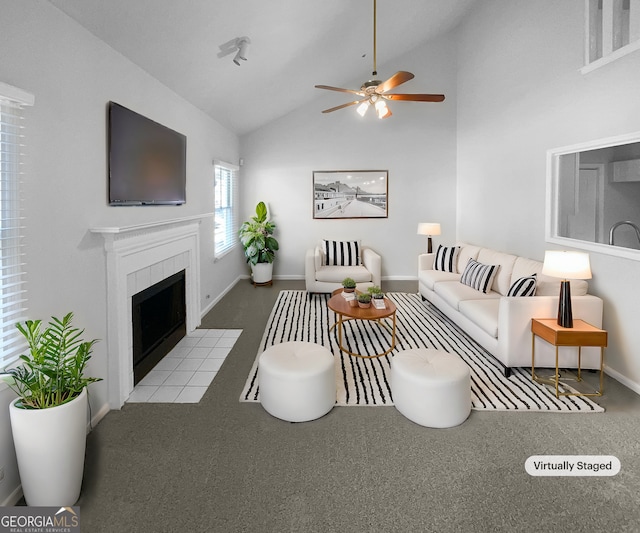 living room featuring lofted ceiling, a tile fireplace, ceiling fan, and light carpet