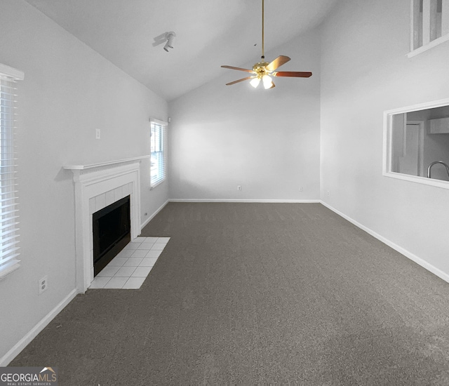 unfurnished living room with ceiling fan, a tile fireplace, vaulted ceiling, and light colored carpet