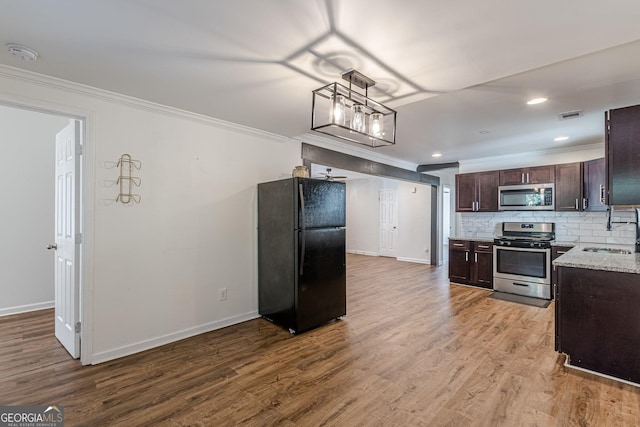 kitchen featuring stainless steel appliances, sink, light hardwood / wood-style floors, decorative backsplash, and dark brown cabinets