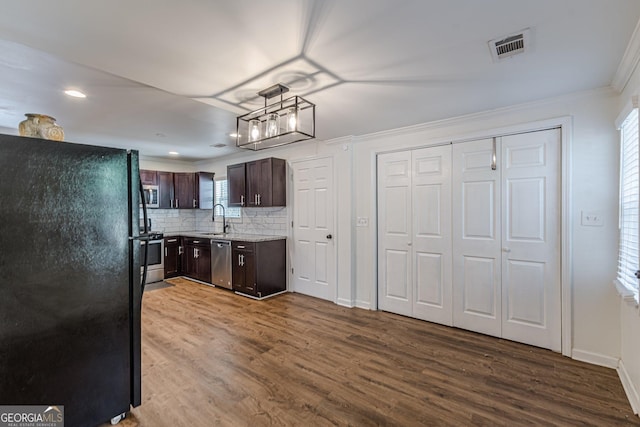 kitchen featuring stainless steel appliances, hardwood / wood-style flooring, sink, dark brown cabinets, and backsplash