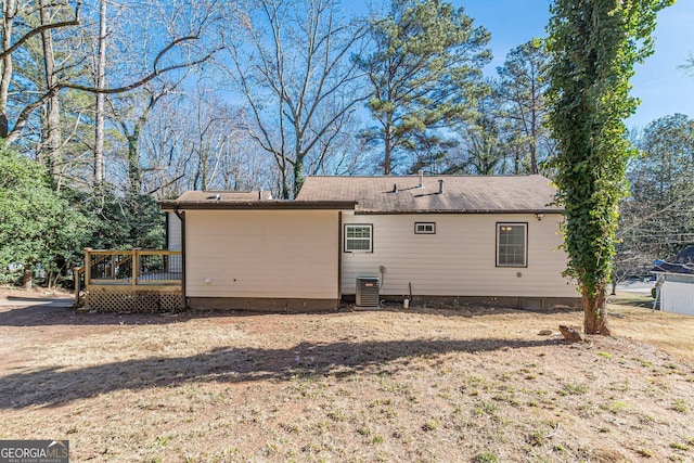 rear view of house featuring a deck, central AC unit, and a lawn