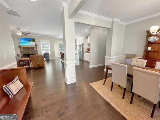 dining room featuring ornate columns, ornamental molding, ceiling fan, and dark wood-type flooring