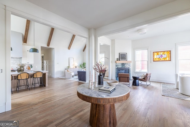 living room featuring light wood-type flooring and vaulted ceiling with beams