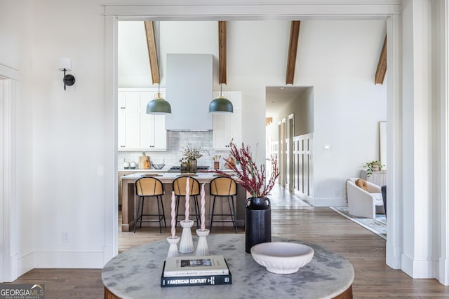 kitchen featuring white cabinets, dark wood-type flooring, tasteful backsplash, lofted ceiling with beams, and a breakfast bar area