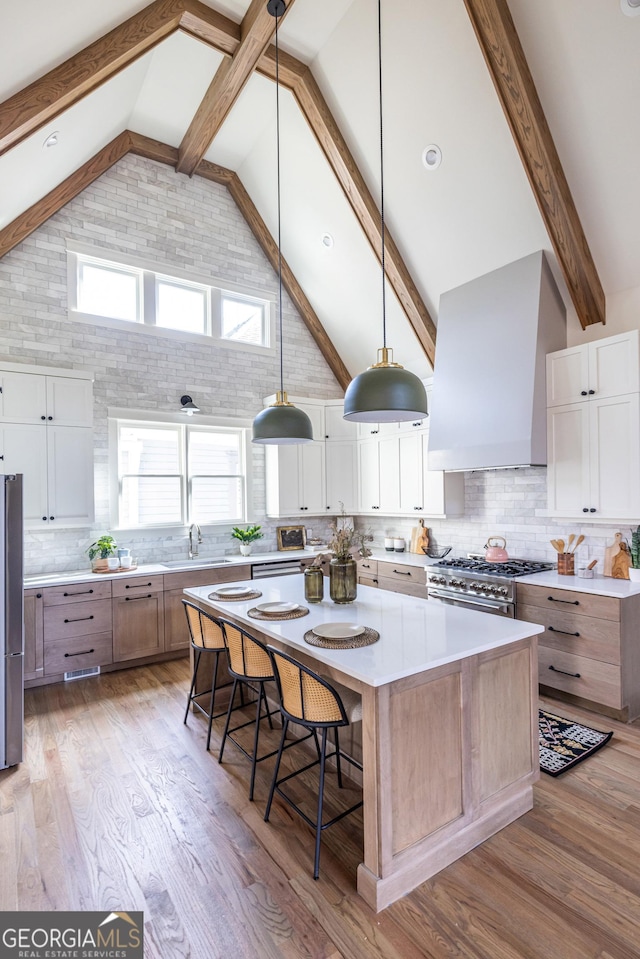 kitchen with white cabinets, stainless steel appliances, a large island, and wall chimney exhaust hood