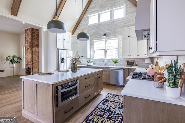 kitchen with decorative light fixtures, a kitchen island, stainless steel appliances, high vaulted ceiling, and white cabinets