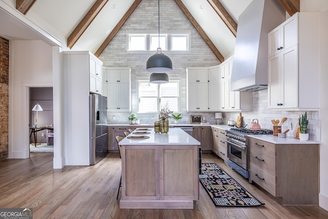 kitchen featuring white cabinetry, island exhaust hood, stainless steel appliances, hanging light fixtures, and high vaulted ceiling