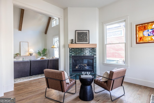 living area featuring a healthy amount of sunlight, vaulted ceiling with beams, and hardwood / wood-style floors