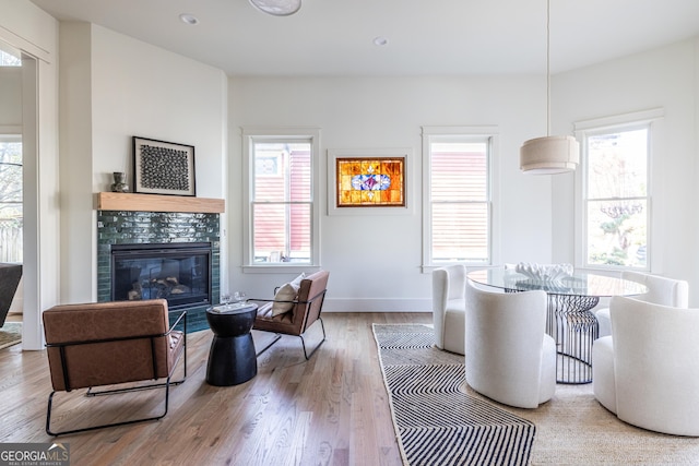 living room with light wood-type flooring, a healthy amount of sunlight, and a tile fireplace