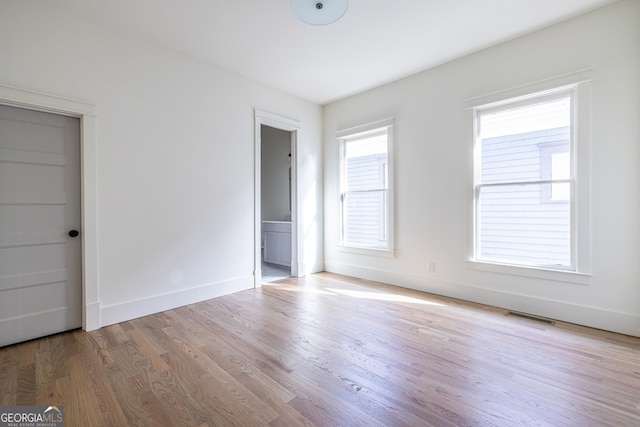 unfurnished bedroom featuring ensuite bathroom and light hardwood / wood-style floors