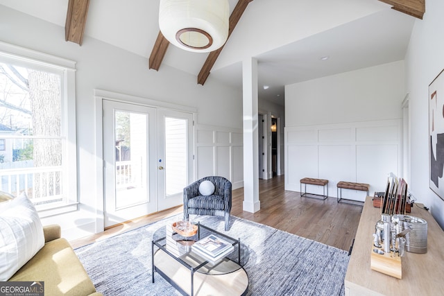 living room with vaulted ceiling with beams, light hardwood / wood-style flooring, and french doors