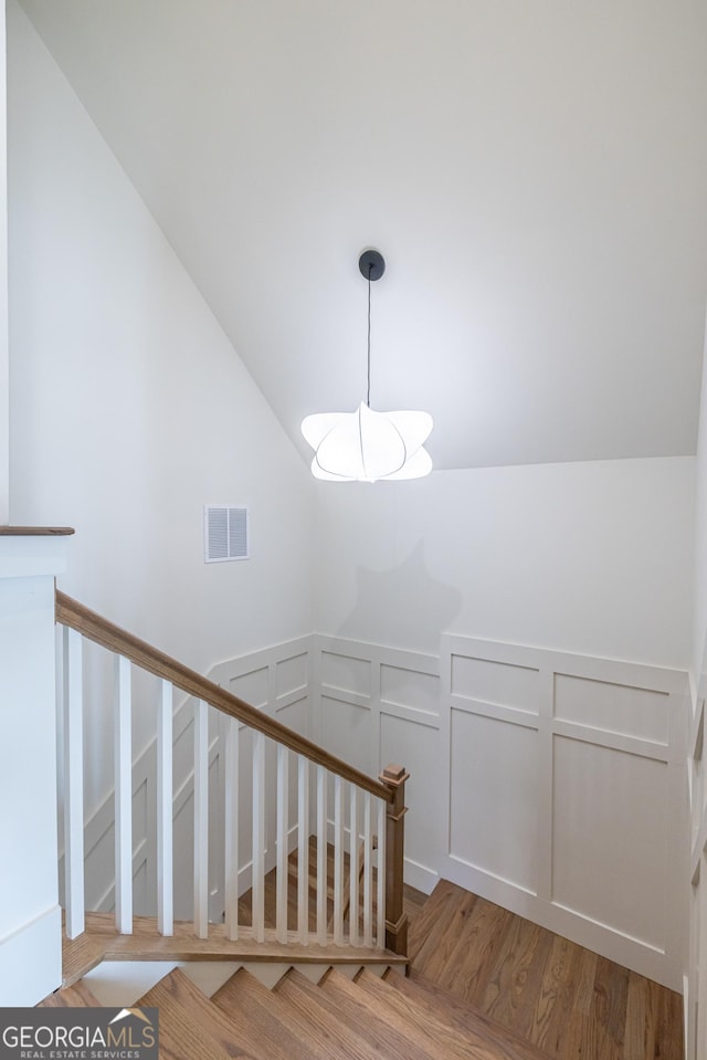 staircase featuring wood-type flooring and vaulted ceiling